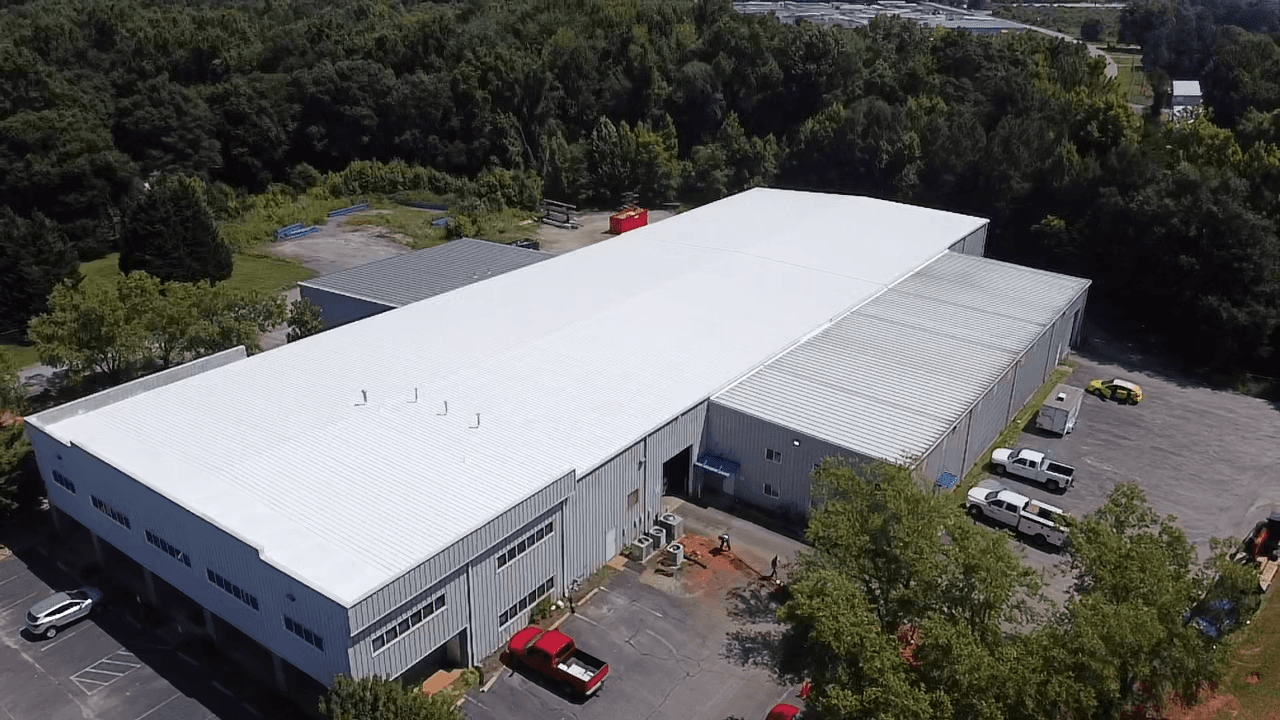 An overhead aerial view of a large commercial building with white metal roofing.