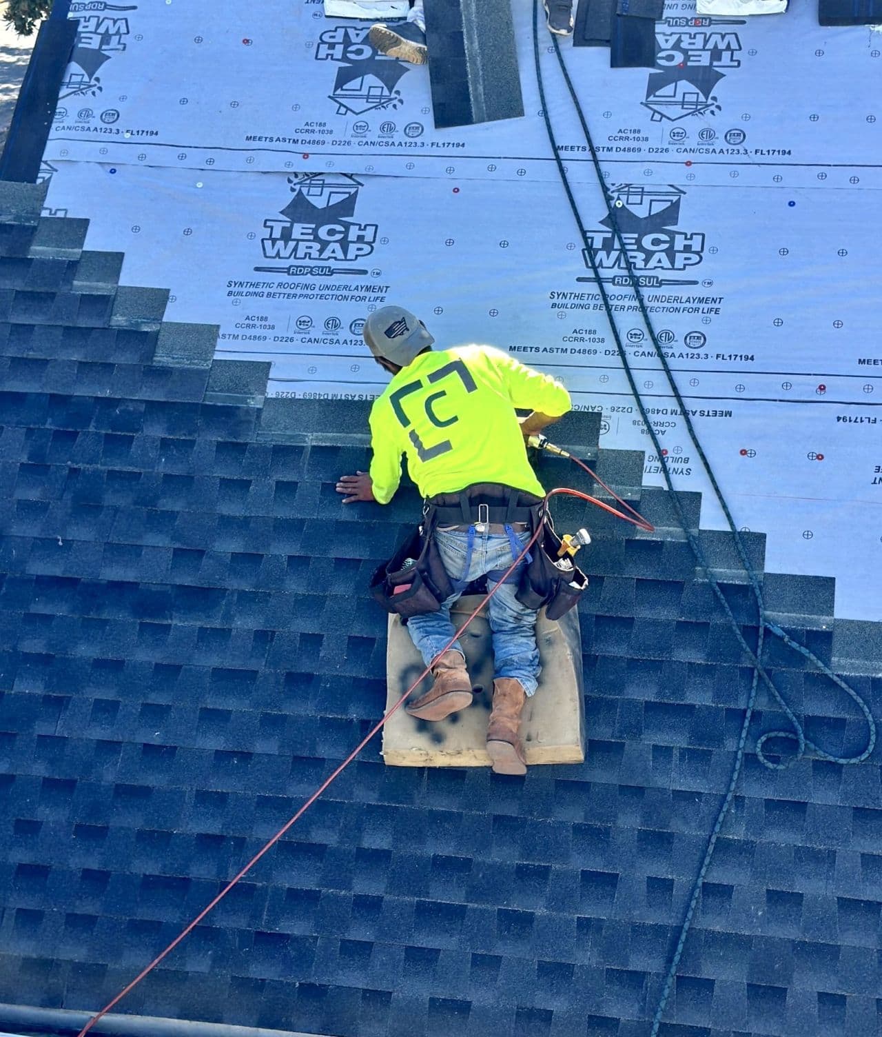 A worker installs roofing shingles.
