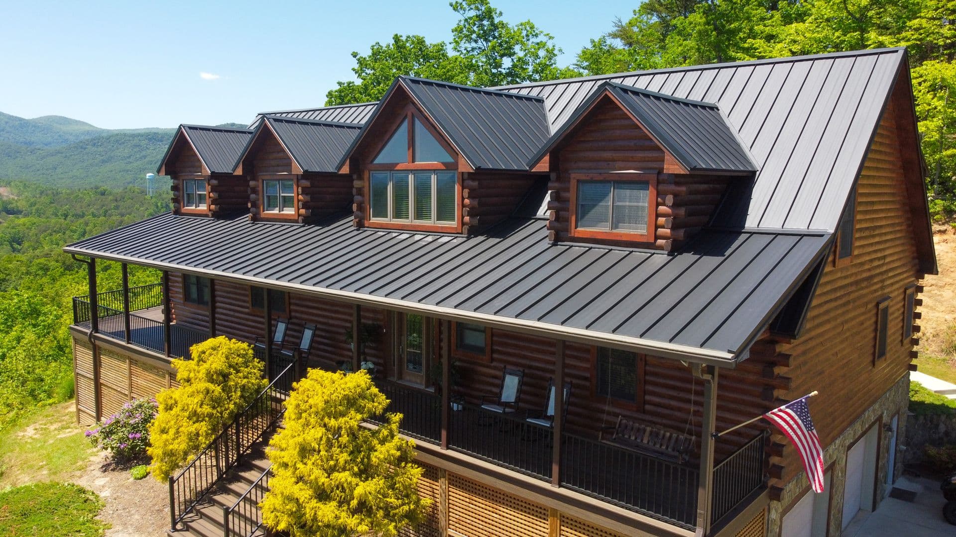 A brown log cabin style home with black standing seam metal roofing.