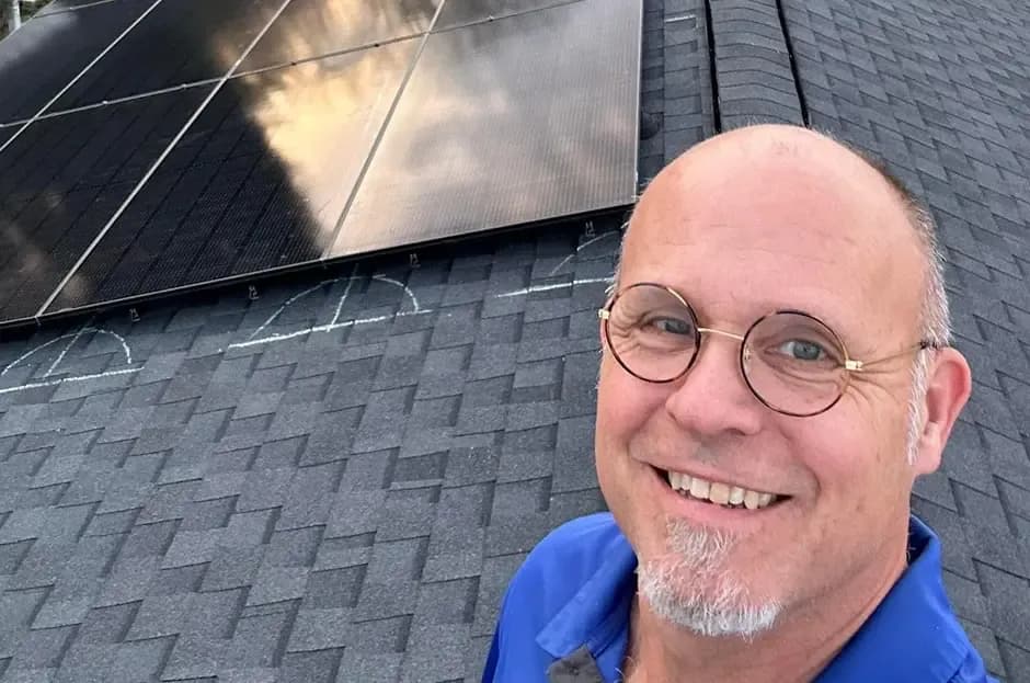 A worker smiles on a roof.