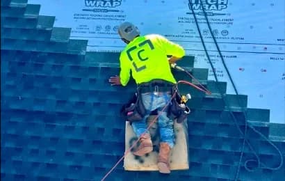 A worker installs roofing shingles.