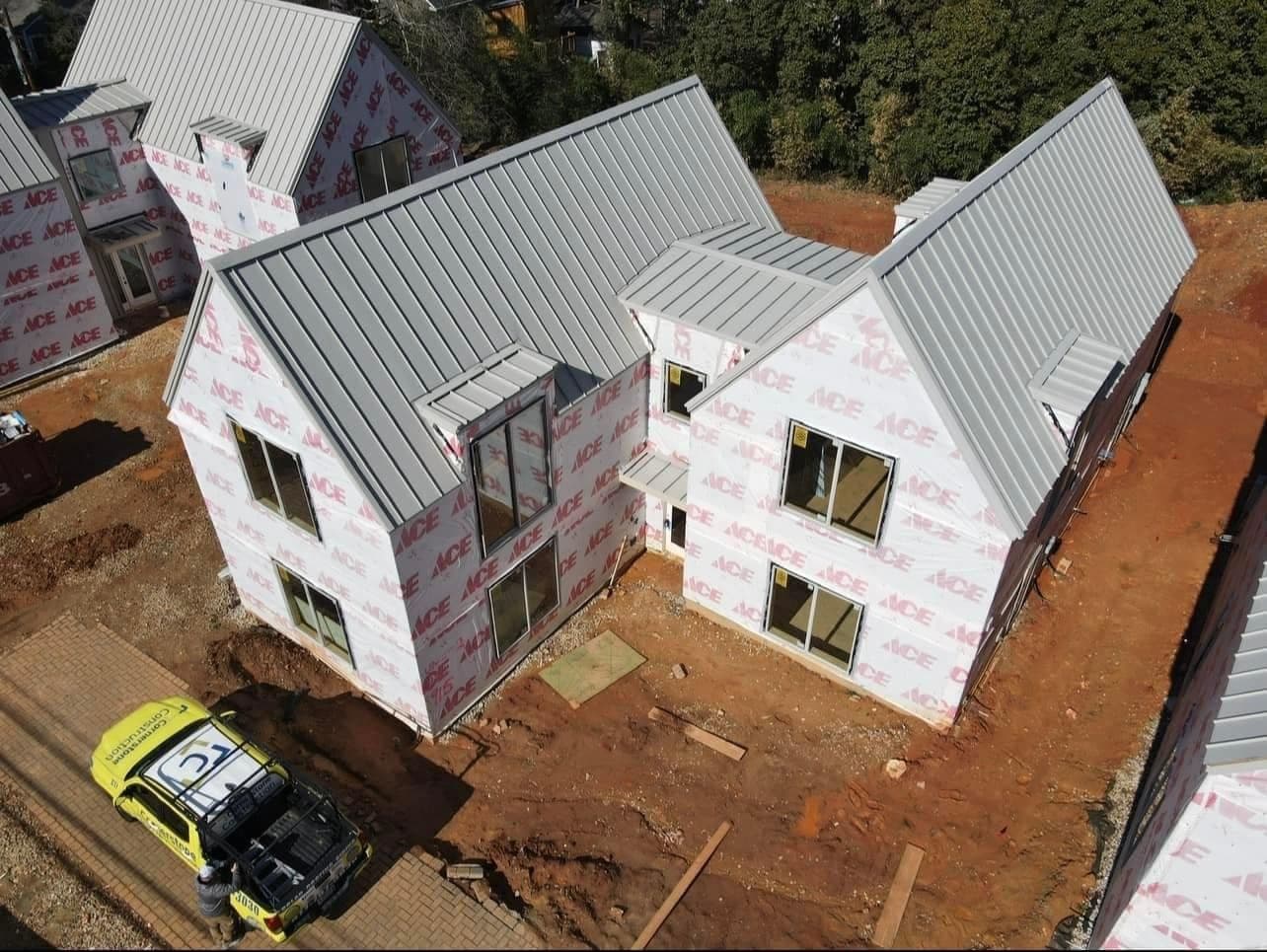 An aerial view of a home mid-construction with a newly-installed light gray standing seam roof.
