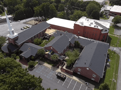 An overhead aerial view of a large church with new roofing.