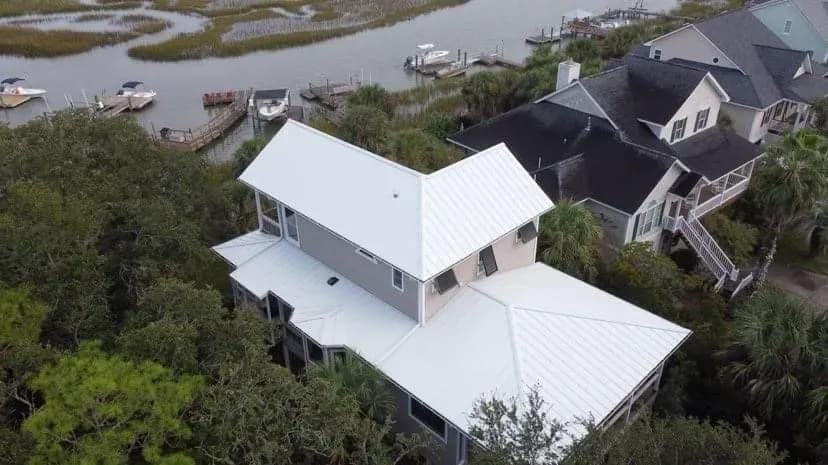A two-story home with new white metal standing seam roofing.