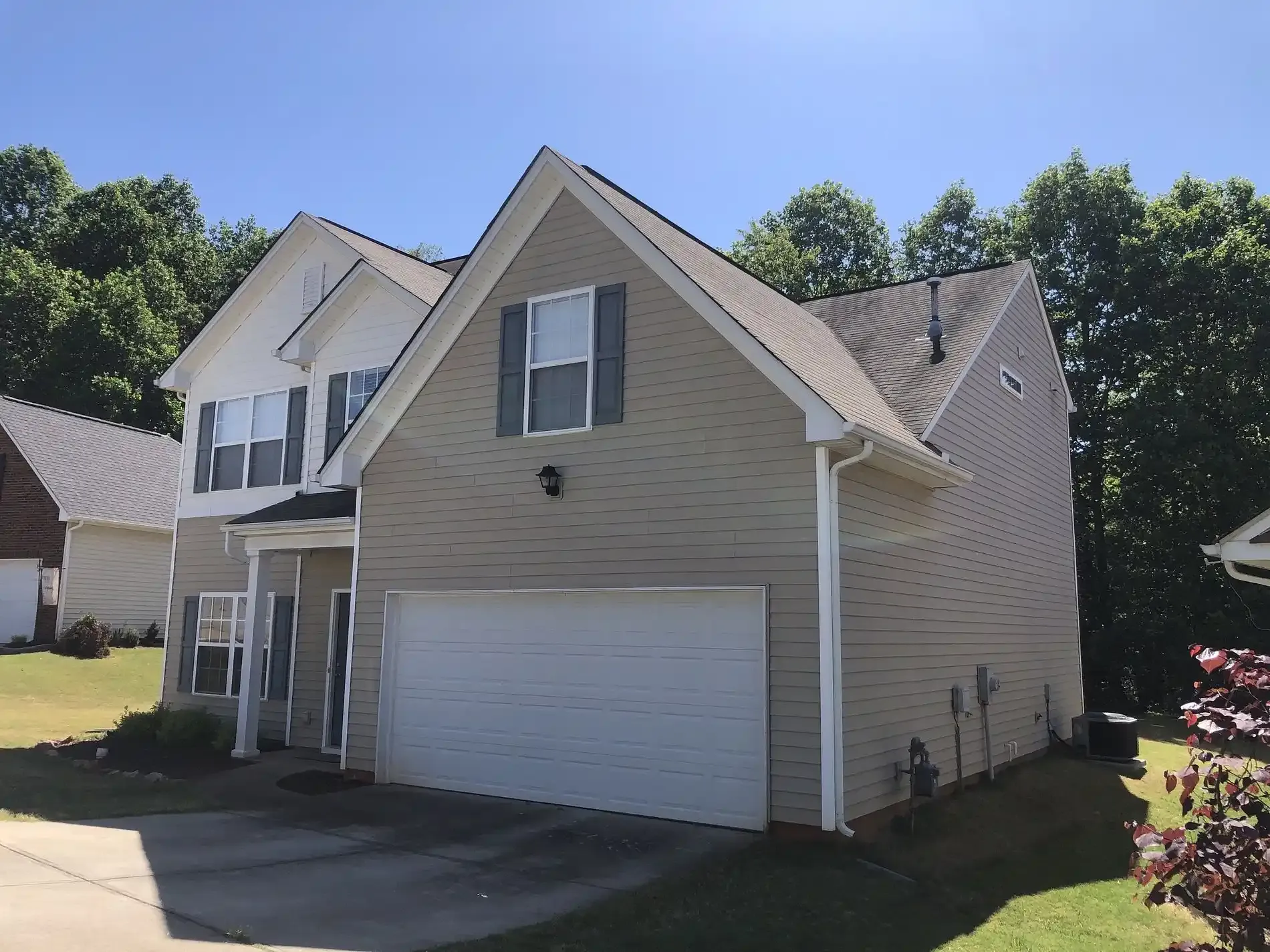 A white and brown house with new tan siding and a large one-car garage.