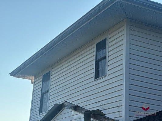 A white house with siding installed by Cornerstone Construction.