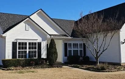 A house with new white siding and black shutters.
