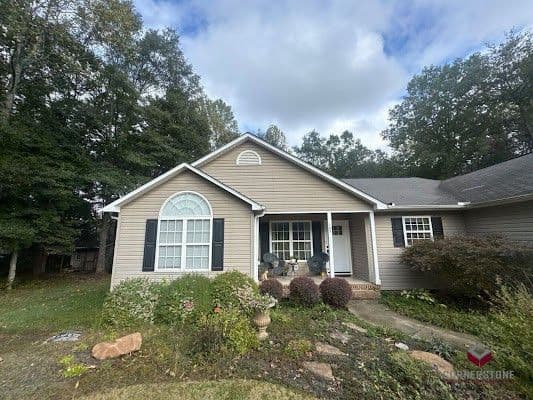 A house with new tan siding and black shutters.
